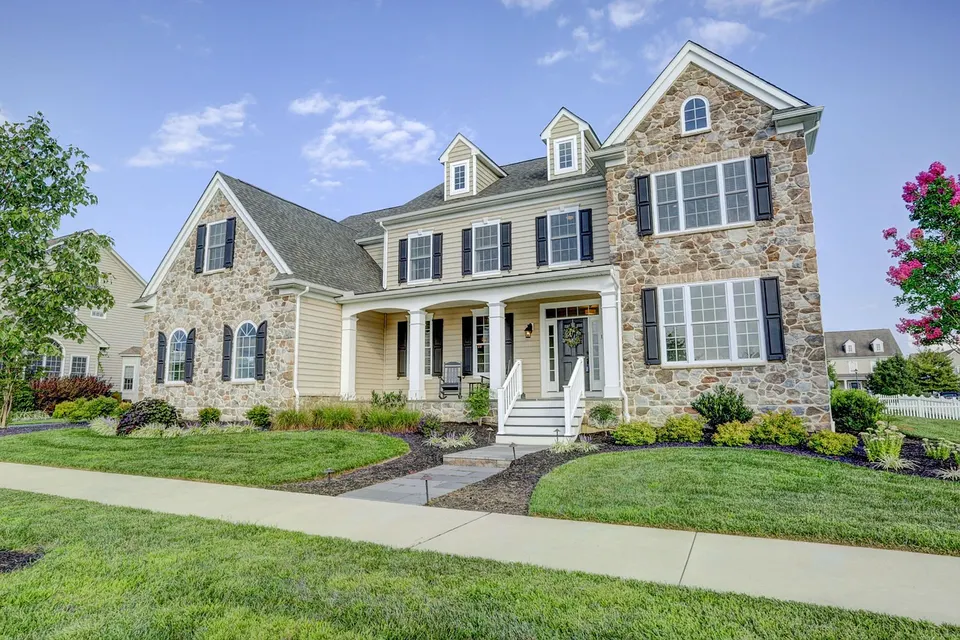 A thick green front lawn in front of a stone house